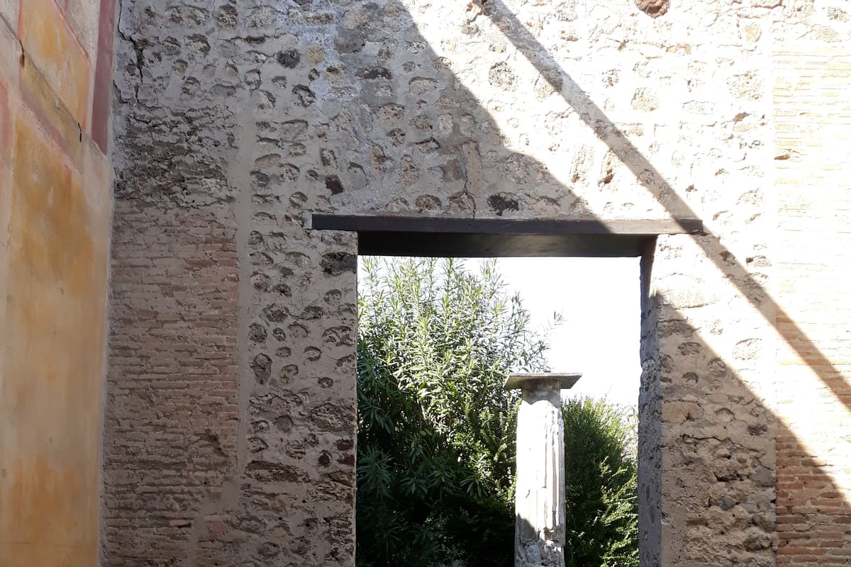 The ruins of Pompeii with Mount Vesuvius rising behind — the forum colonnade, basalt street paving, and the volcano that buried the city in 79 AD. UNESCO World Heritage since 1997.